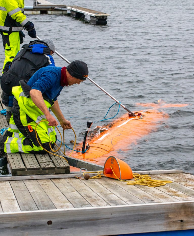 Undervannsfarkosten Hugin på ved brygga, der tre menn tar den imot.