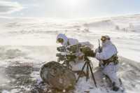 To soldater i vinterbekledning monterer utstyr i vinterlandskap