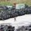 et oversiktsbilde viser en stor plass med mange stridsvogner og andre militære kjøretøy som er parkert. Midt på plassen går en mann i hæruniform
